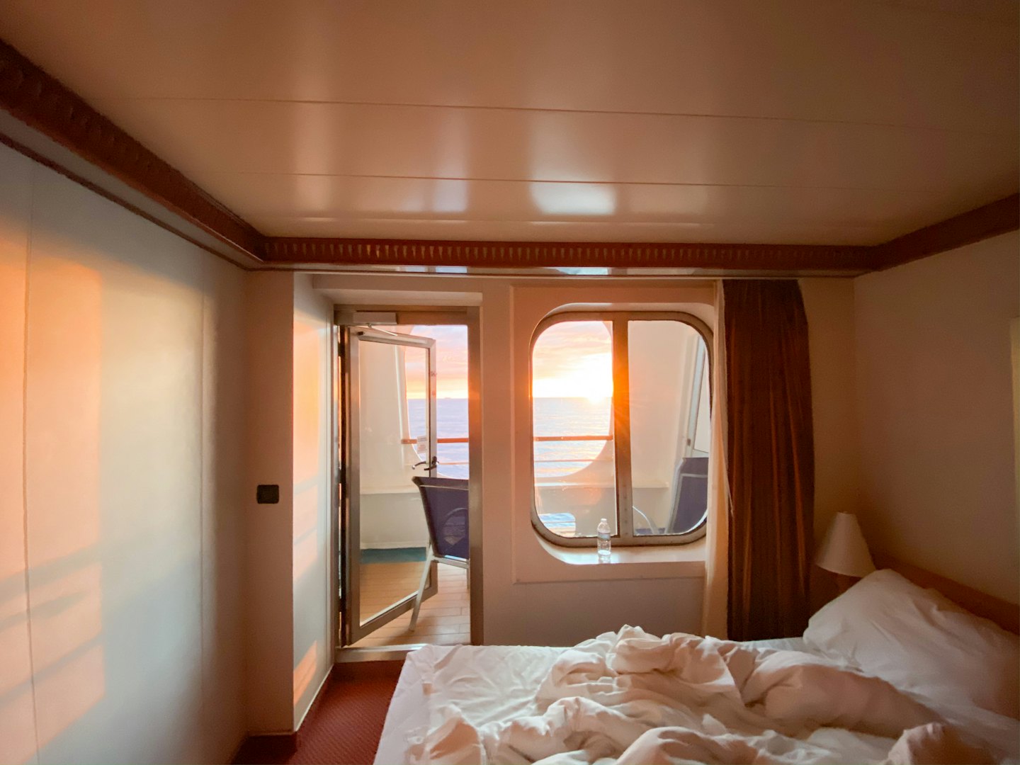 Eine Kreuzfahrtschiffkabine mit Balkon und Meerblick.
