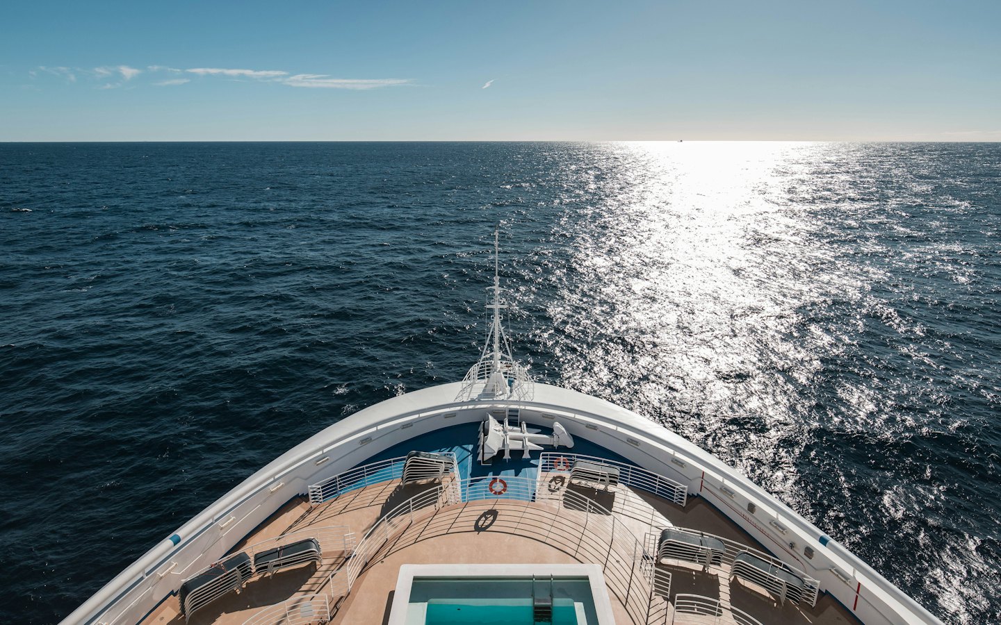Weißes Kreuzfahrtschiff fährt über das tiefblaue Meer.
